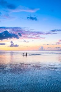 Silhouette people on sea against sky during sunset