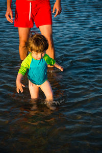 Midsection of father with daughter wading in sea
