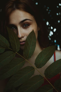 Close-up portrait of young woman with leaves