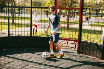 A young man in a sports uniform trains with a ball on the freestyle football court. 