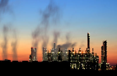 Illuminated factory against sky at night