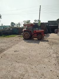 Tractor on road by field against sky