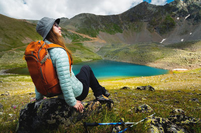 A woman sits in a vantage point above a stunning turquoise lake surrounded by mountains during the