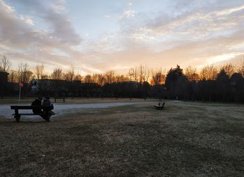 People on field against sky during sunset