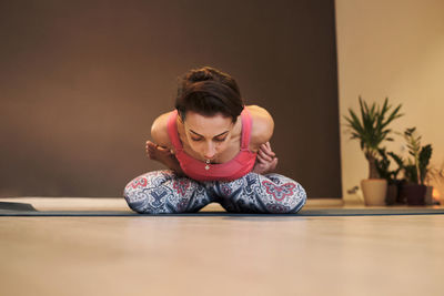 Young woman doing yoga on yoga mat in atmospheric yoga studio