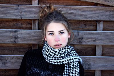 Portrait of teenage girl standing against wooden wall