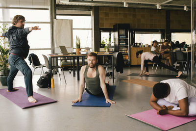 Business colleagues exercising on mats at office