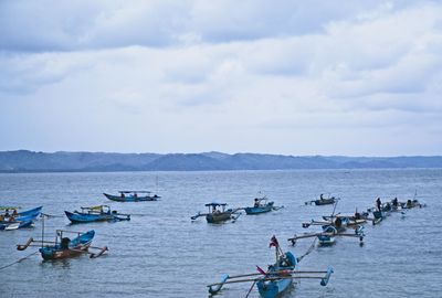 Boats moored in sea against sky