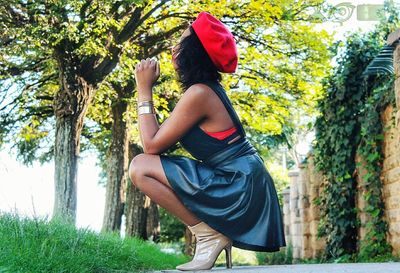 Low angle view of young woman standing by tree