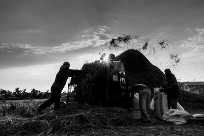 Rear view of people sitting on grassy field