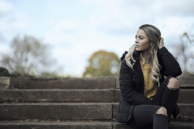 Full length of young woman sitting outdoors