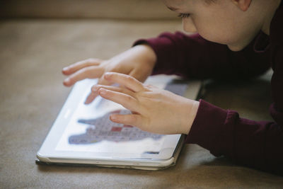 Cute boy playing video game in digital tablet at home