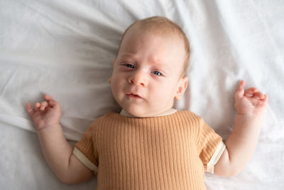 Portrait of cute baby girl lying on bed at home