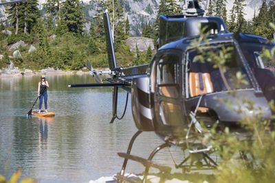 Woman paddle boards on remote lake accessed by helicopter.