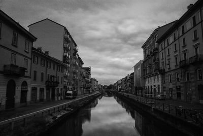 Canal in city against sky