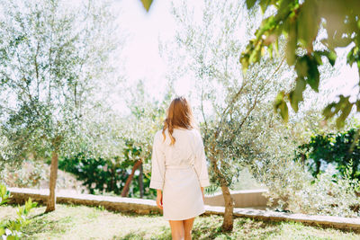 Rear view of woman standing against trees