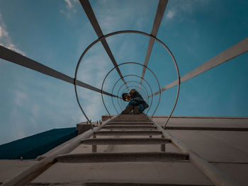 Low angle view of man climbing up against sky