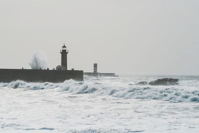 Lighthouse by sea against clear sky