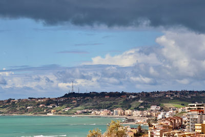 Aerial view of townscape by sea against sky