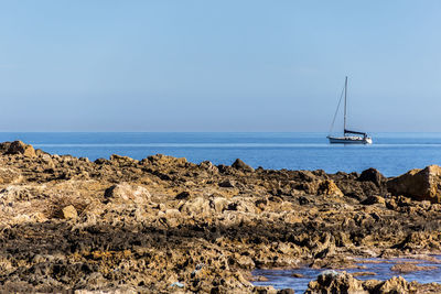 Sailboat on sea shore against sky