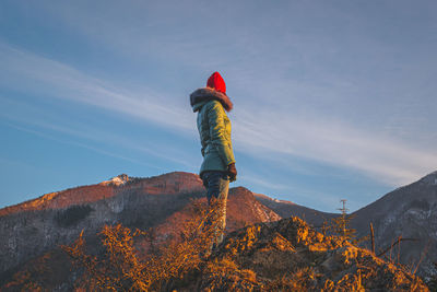 A young caucasian redhead woman standing in the french alps mountains in winter at sunset