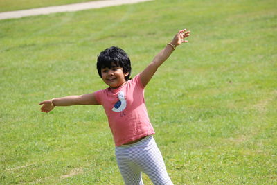 Full length of girl standing on field with hands wide open