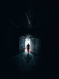 Rear view of silhouette man walking in dark footpath