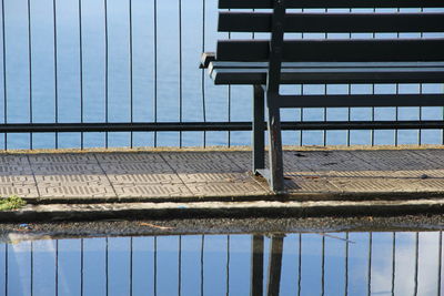 Bench by swimming pool against sky