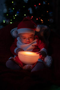 Midsection of child in illuminated christmas tree