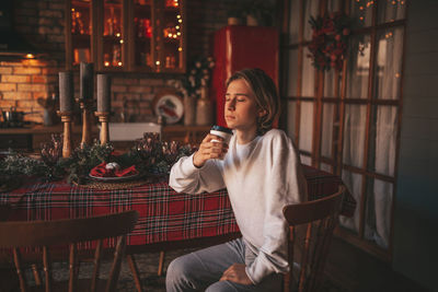 Portrait of candid authentic smiling handsome boy teenager using mobile phone at xmas home interior