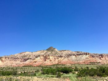 Scenic view of arid landscape against clear blue sky