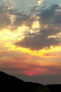 Scenic view of landscape against cloudy sky at sunset