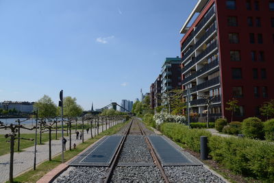 Railroad tracks amidst buildings in city against sky