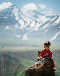 Woman sitting on rock against mountain