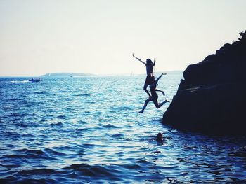 Silhouette man surfing in sea against sky