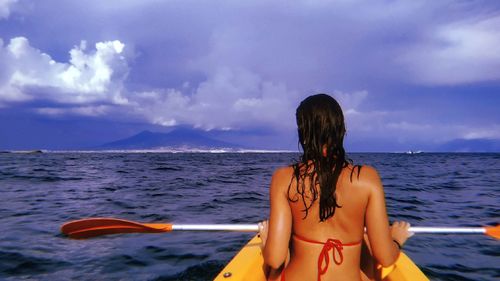 Rear view of woman in sea against sky