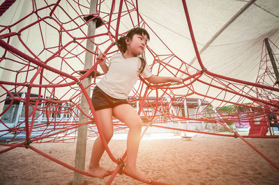 Low angle view of girl on play equipment at playground