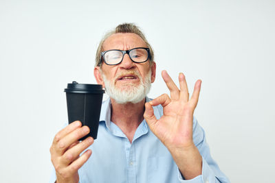 Portrait of senior man with coffee cup against white background