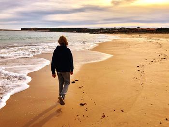 Rear view of boy walking at beach