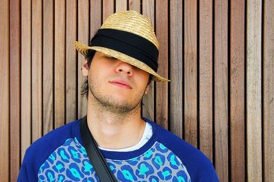 Portrait of man wearing hat standing against wall