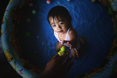 Cropped hand giving toy to daughter in bathtub