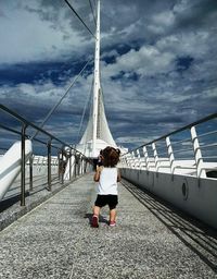 Rear view of woman running on bridge against sky