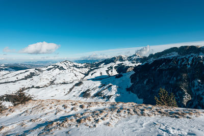 Scenic view of snowcapped mountains against blue sky