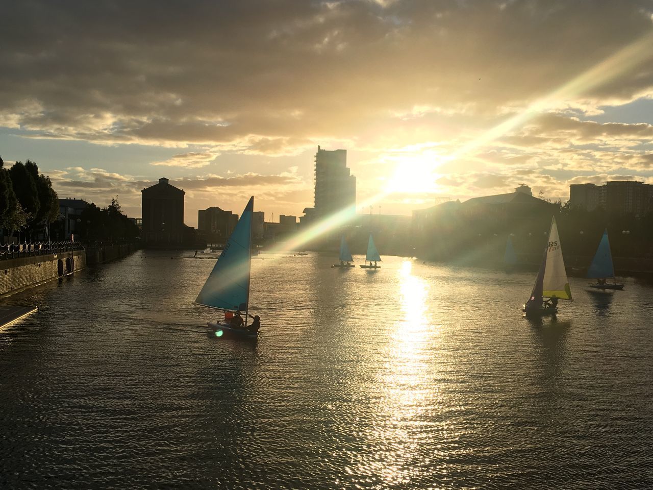 SAILBOATS IN RIVER AGAINST SKY AT SUNSET