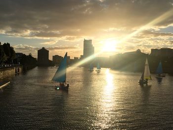 Sailboats in river against sky during sunset