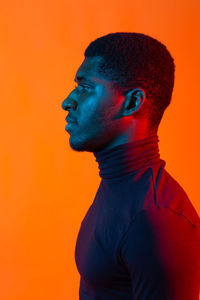 Close-up portrait of young man against orange background