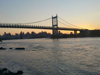 Suspension bridge over river at sunset
