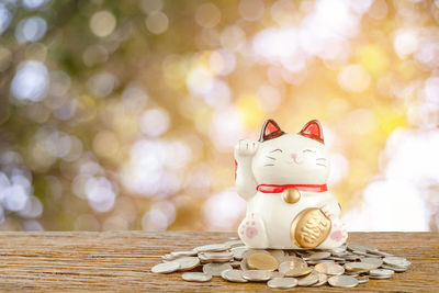 Close-up of maneki neko with coins on wooden table