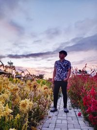 Rear view of man standing on flower against sky