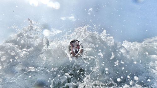 Low angle view of girl amidst wave in sea